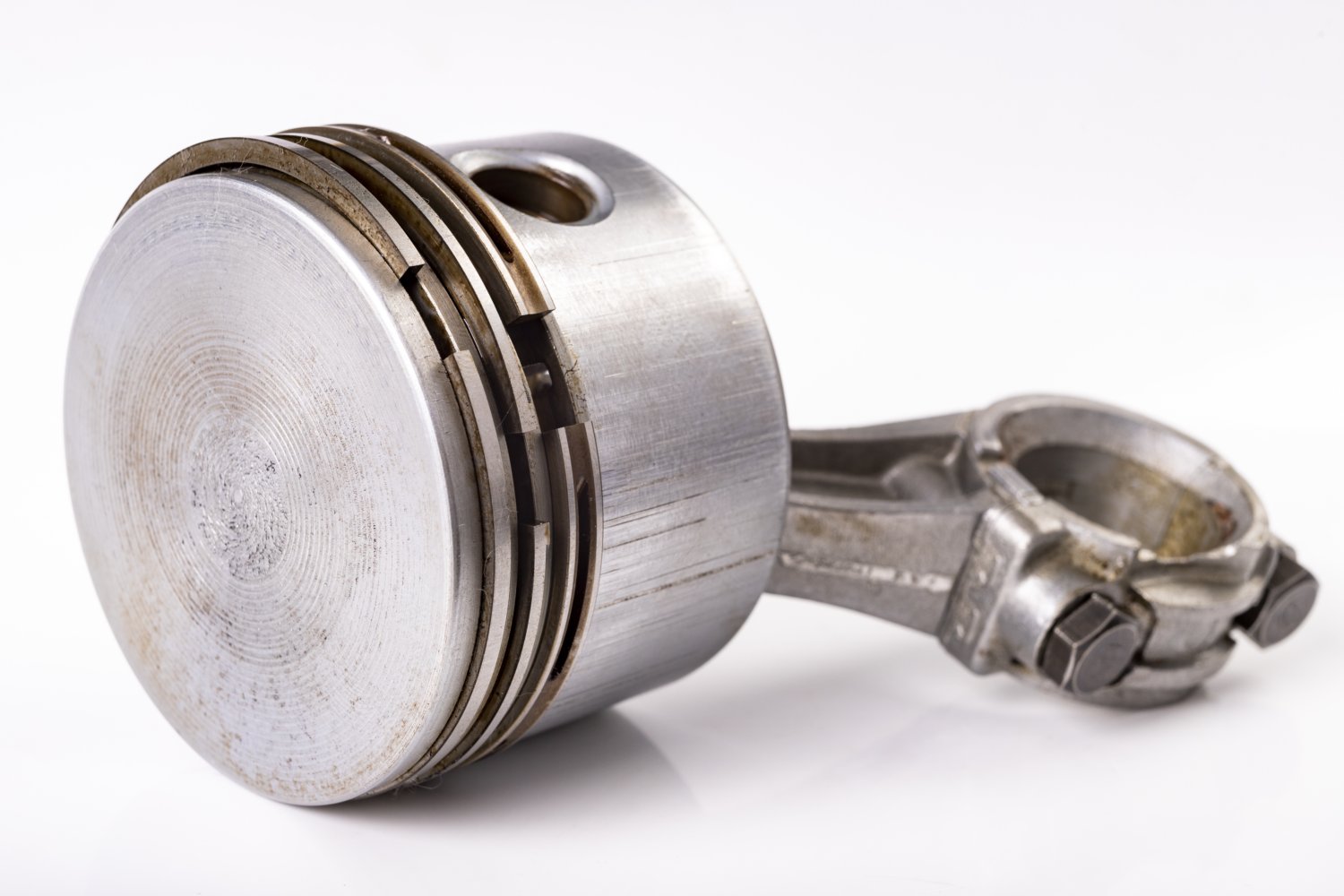 Piston and connecting rod of a small internal combustion engine. Spare parts for engine repair and regeneration. Light background.