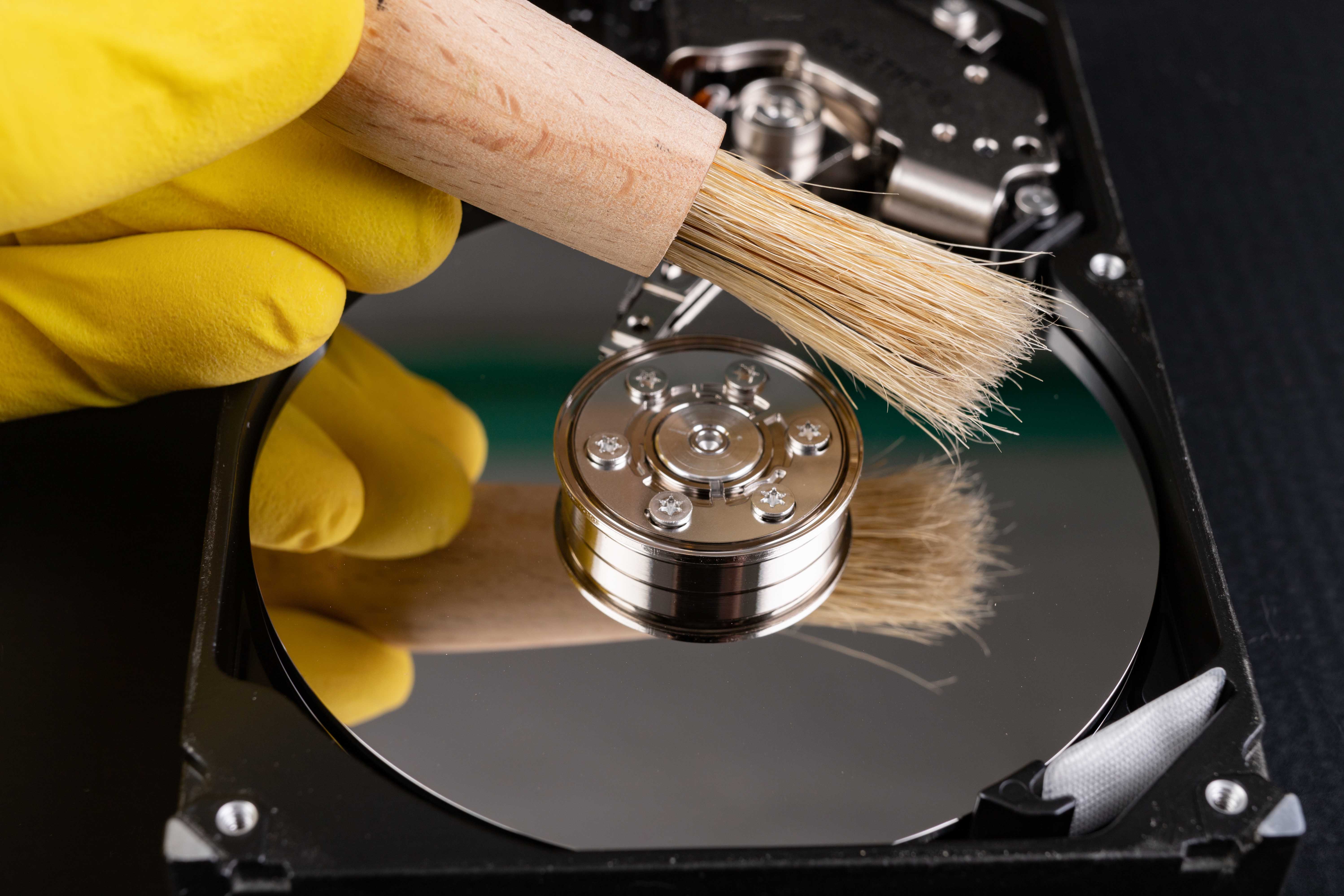 Cleaning the hard disk with a brush. Vacuuming old disk data on your computer. Dark background.
